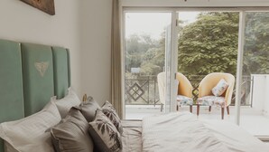 Ein Schlafzimmer mit einem grünen Kopfteil, einem großen Bett und einem Balkon mit zwei Stühlen.