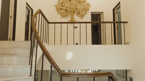 Eine Holztreppe mit Geländer führt zu einem Essbereich mit Tisch und Stühlen.