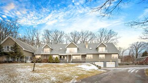 A two-story house with a garage, a covered porch, and a small front yard with snow patches.