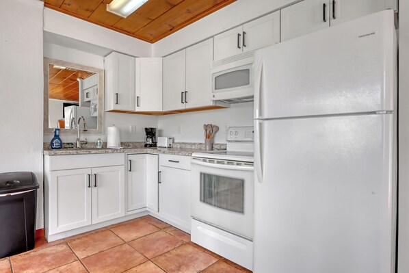 A kitchen with white cabinets, a microwave, a refrigerator, and a stove.