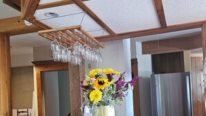 Een houten eettafel met een bloemenvaas, houten krukken en een hanglamp.