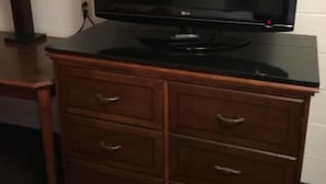 En tv-apparat står på ett träskåp i ett hotellrum.