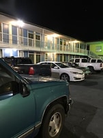 Un estacionamiento con varios coches aparcados frente a un motel de varios pisos y balcones.