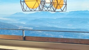 Una mesa con una botella de Valdo Prosecco y tres copas, con vistas a un paisaje montañoso.