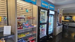 Un bar de aperitivos con estantes llenos de papas fritas, bocadillos y bebidas. Hay carteles que indican zonas 'RECHARGE' y 'HYDRATE'.
