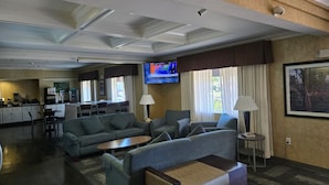 Una habitación de hotel con sala de estar, kitchenette y televisión.