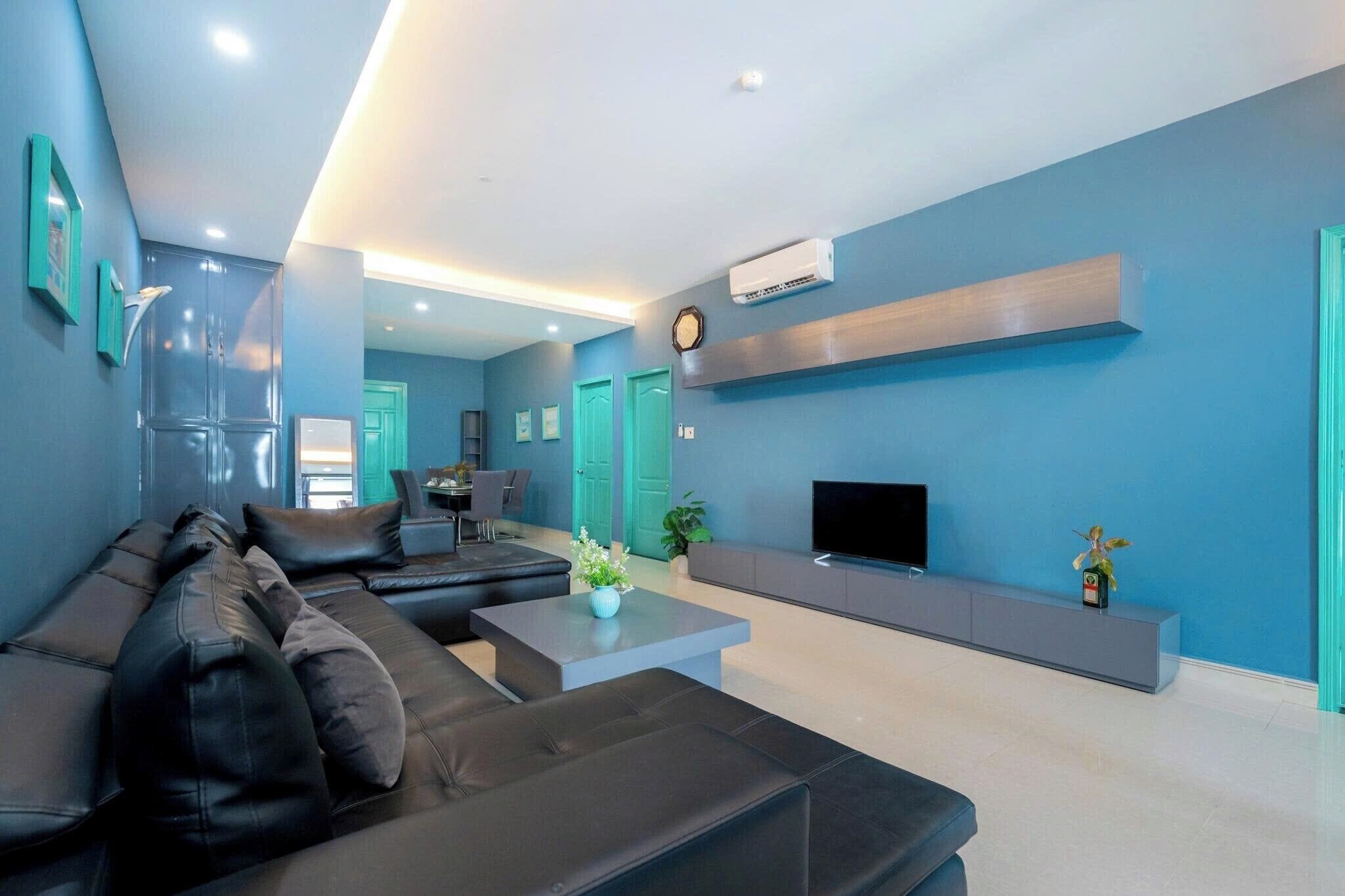 Een moderne woonkamer met een zwarte leren bank, een salontafel, een flatscreen televisie en een minimalistisch ontwerp.