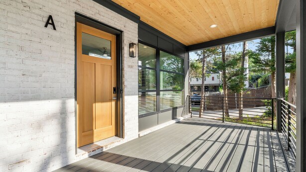 A modern building with a wooden deck, a brick wall, and a large window. - Modern Luxury in West Midtown 4BR with Rooftop (Atlanta)