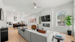 A modern living room with a grey sofa, a black coffee table, and a TV mounted on the wall. - Modern Luxury in West Midtown 4BR with Rooftop (Atlanta)