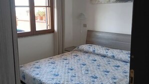 A bedroom with a bed, a window, a lamp, and a wall decoration. - House Relax sea view Sardinia (Funtana Meiga)