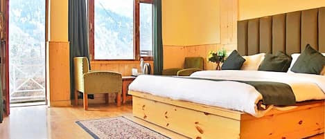 Un dormitorio de madera con cama, una silla, un escritorio y vistas a montañas a través de amplios ventanales.