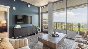 A modern living room with a large TV, a sofa, a coffee table, and a balcony with a view. - Landing | Beautiful 2BD, Gym (St. Petersburg)