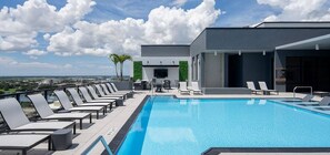 A rooftop pool with lounge chairs and a view of the city. - Landing | Amazing 2BD, Gym (St. Petersburg)