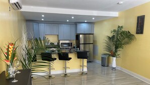 A modern kitchen with grey cabinets, stainless steel appliances, and a central island with bar stools. - Toraille Waterfall Villas (Soufriere)