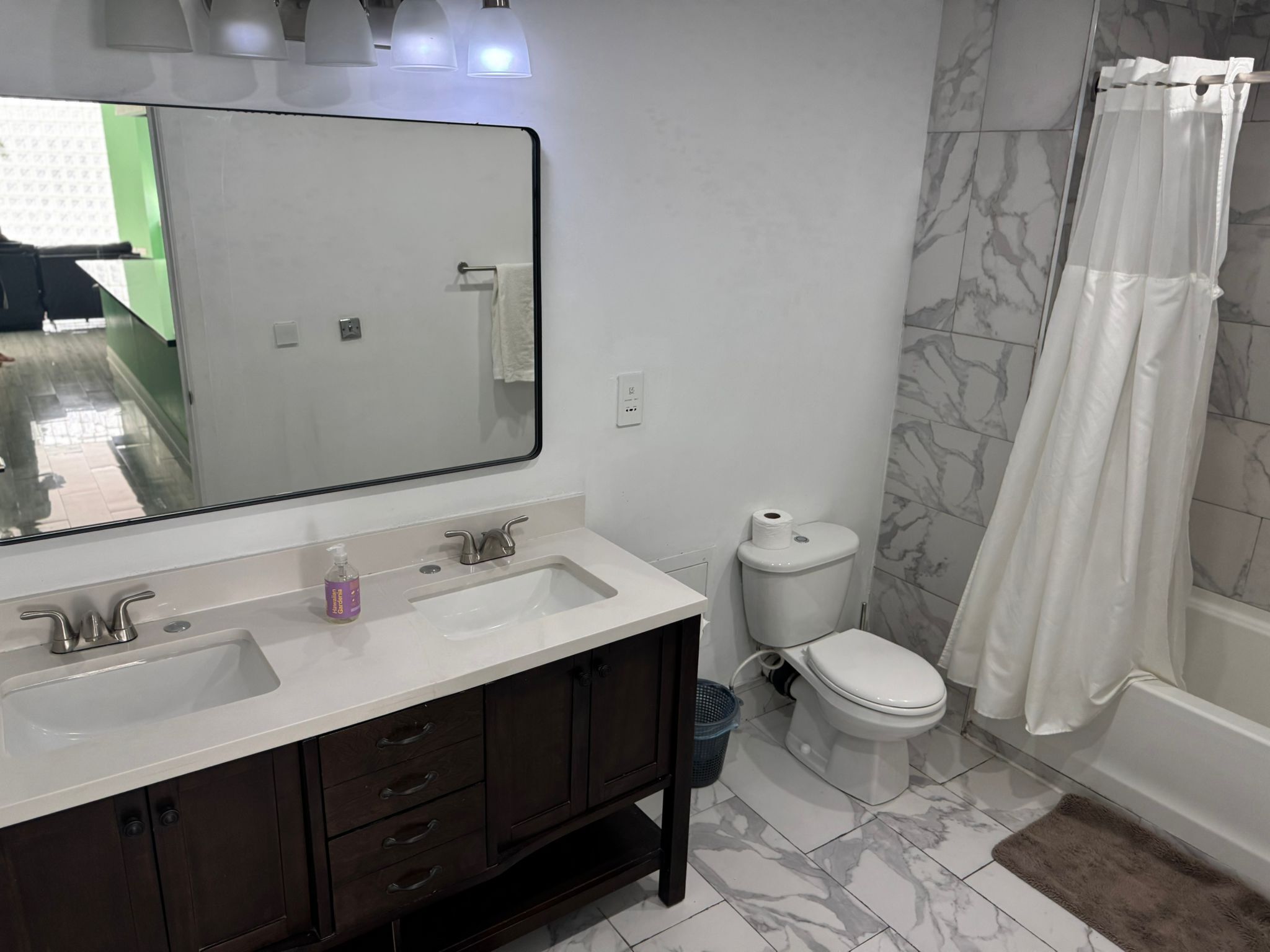 A bathroom with a white sink, dark wooden cabinets, a toilet, and a shower with a white curtain.