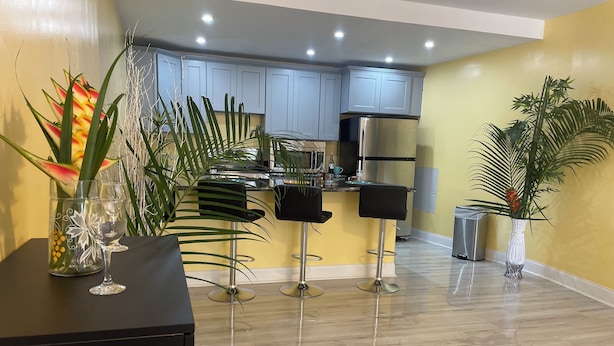 A modern kitchen with light blue cabinets, a stainless steel refrigerator, and a bar area with two stools. - Toraille Waterfall Villas (Soufriere)