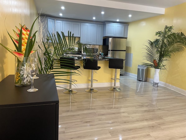 A modern kitchen with light blue cabinets, a stainless steel refrigerator, and a bar area with two stools. - Toraille Waterfall Villas (Soufriere)