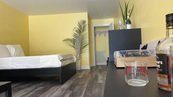A room with a bed, a desk, a potted plant, a bottle, and a cabinet.