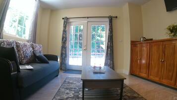 A living room with a sofa, a coffee table, a wooden cabinet, and a door leading outside.