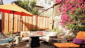 A wooden deck with outdoor furniture, including a white sofa, a wicker chair, and a lounge chair. - Spacious 2BR Potrero Hill Home  Minutes to Moscone & Caltrain for Super Bowl (San Francisco)