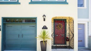 A two-story building with a teal garage door and a red door with a wreath. - Spacious 2BR Potrero Hill Home  Minutes to Moscone & Caltrain for Super Bowl (San Francisco)