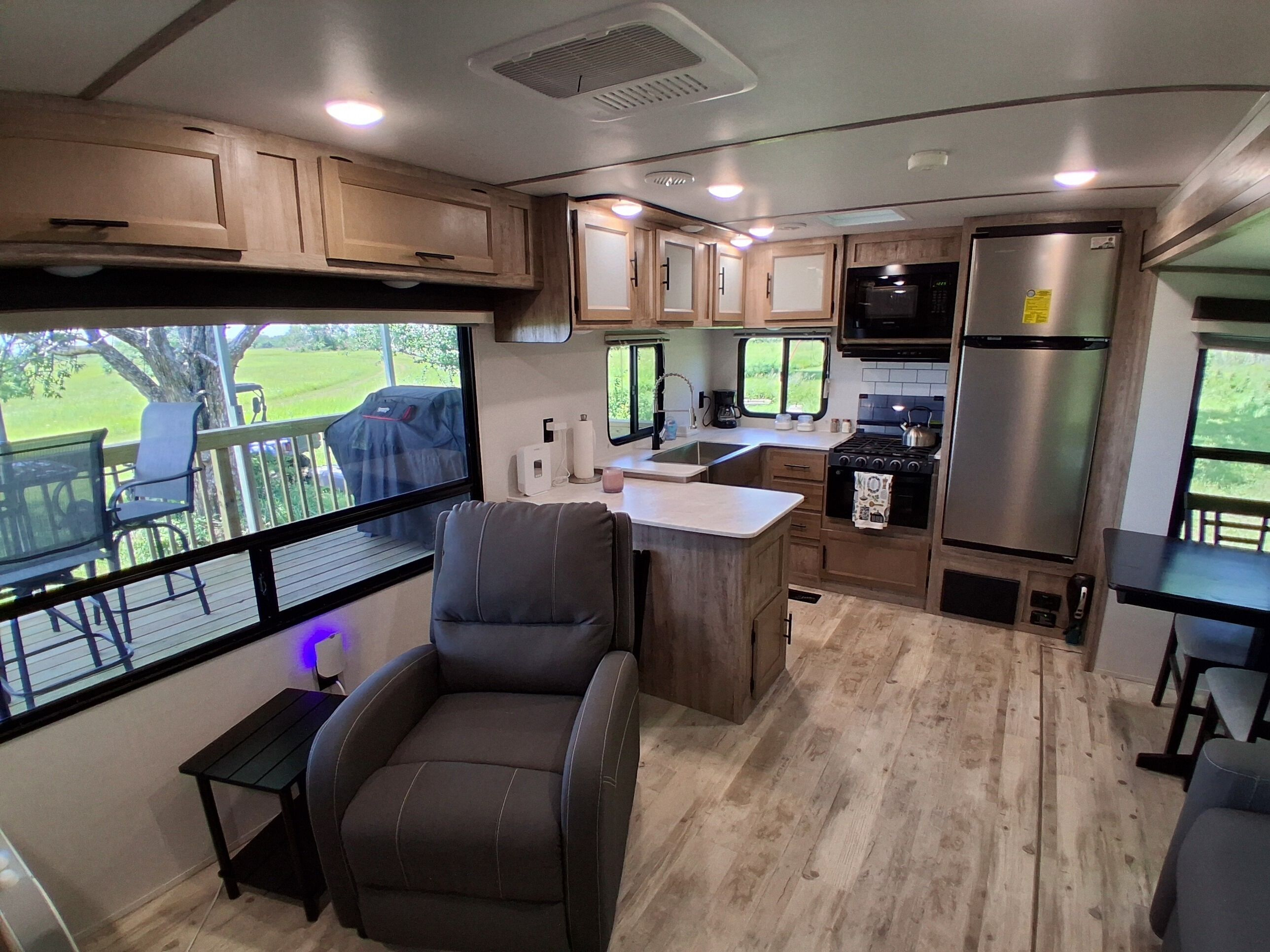 A compact RV kitchen with a dining area, a seating space, and a view of the outdoors.
