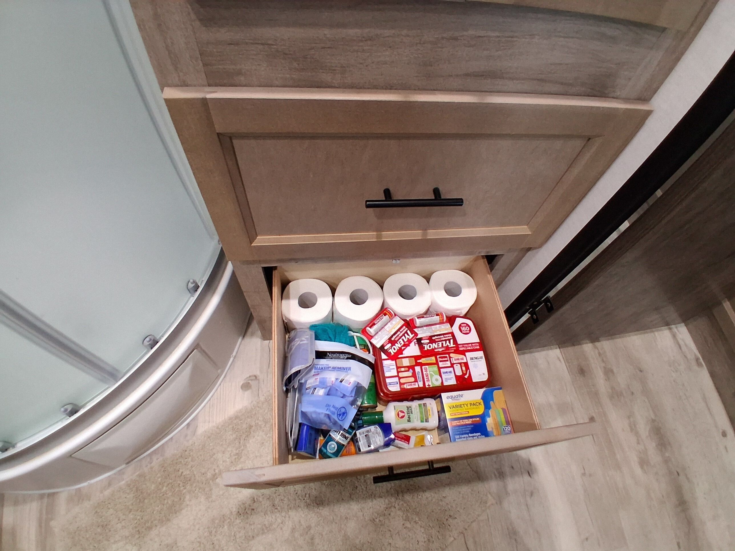En skuffe med toiletpapir, rengøringsmidler og forskellige personlige plejeartikler.