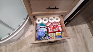 A drawer with toilet paper, cleaning supplies, and a variety of personal care products.