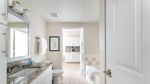 A modern bathroom with a granite countertop, a toilet, a sink, and a bathtub. - Landing | Modern 1BD, Gym, Pool (Orlando)
