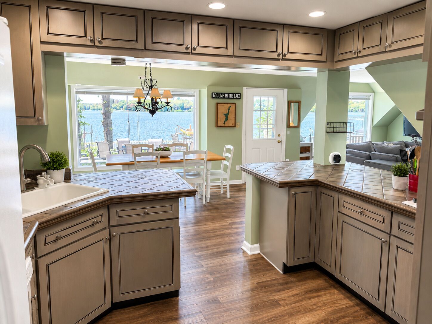 A kitchen with a view of a lake, wooden cabinets, a dining area with a table and chairs, and a kitchen island.