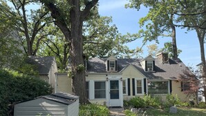 A two-story house with a front door labeled "4205," surrounded by lush greenery and a pathway leading to the entrance.