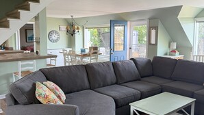 A modern living room with a sectional sofa, a small white table, and a staircase leading to an upper level.