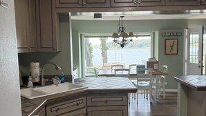 A kitchen with wooden cabinets, a built-in dishwasher, and a view of a lake through the window.