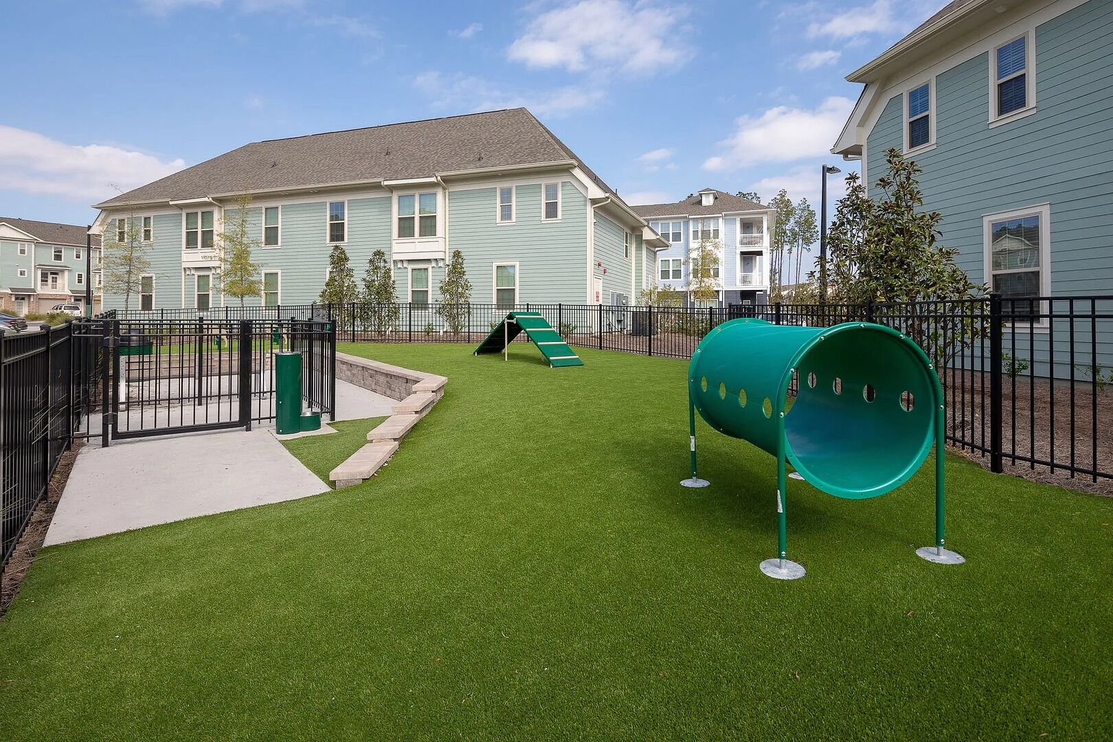 A residential area with houses, a playground with a slide, and artificial grass.