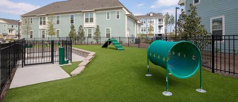 A residential area with houses, a playground with a slide, and artificial grass.