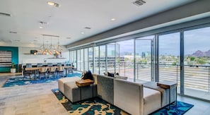 A modern hotel lobby with a dining area, seating, and large windows offering city views. - Landing | Chic 2BD, Gym, Clubhouse (Phoenix)