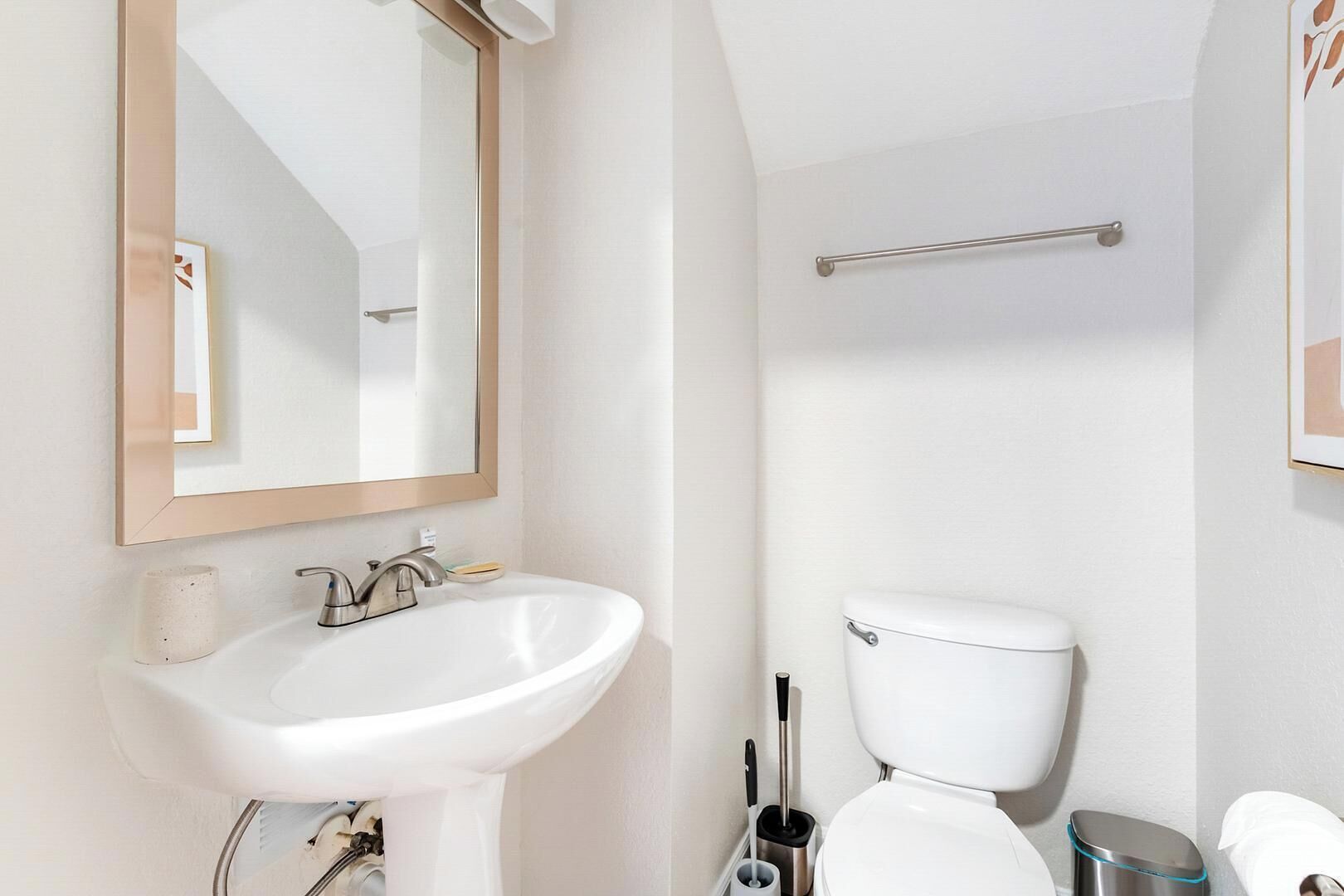 Ein modernes Badezimmer mit einem weißen Waschbecken, einem Spiegel, einer Toilette und einem Handtuchhalter.