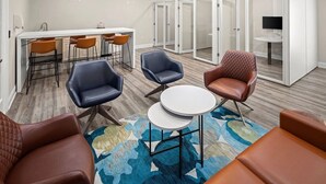 Une salle de réunion moderne avec une table blanche, des fauteuils en cuir et un grand tapis.