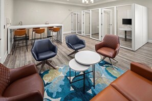 A modern meeting room with a white table, leather chairs, and a large rug.