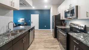 Eine moderne Küche mit dunklen Schränken, Granit Arbeitsplatten, Edelstahlgeräten und einer blauen Akzentwand.