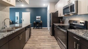 Una cocina moderna con armarios de madera oscura, electrodomésticos de acero inoxidable y una pared de acento azul.