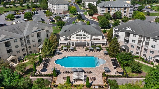 A multi-story residential building with a central courtyard featuring a swimming pool, outdoor seating, and a landscaped garden. - Landing | Stunning 1BD, Gym, Clubhouse (Charlotte)
