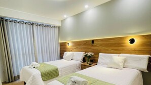 Ein Hotelzimmer mit zwei Betten, einem Holzkopfteil, einem Nachttisch und einem Fenster mit Vorhängen.