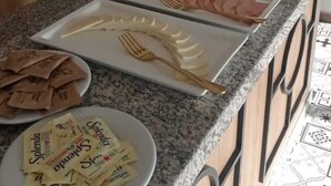 Eine Küchenarbeitsplatte mit Frühstücksartikeln, darunter Wurst, Brot und Gewürzen.