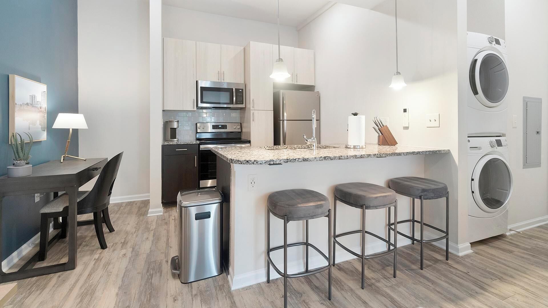 A modern kitchen with a central island, stainless steel appliances, and a built-in washing machine.