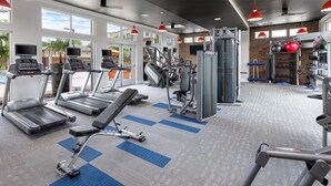 Une salle de sport équipée de tapis de course, d’appareils de musculation et d’une zone dédiée aux exercices de développé couché.