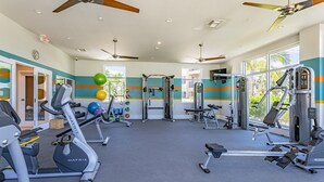 Una palestra con diverse attrezzature per esercizi, tra cui tapis roulant e macchinari per pesi, e un’ampia vetrata che offre luce naturale.