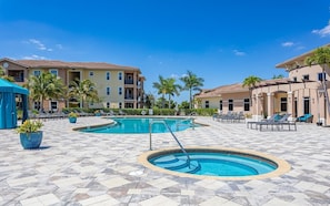 A pool area with two swimming pools, lounge chairs, and palm trees.