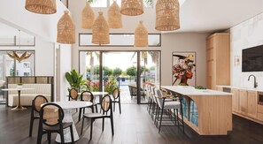 Una cocina moderna con una isla central, luces colgantes y vistas al exterior.