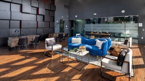 Ein modernes Wohnzimmer mit einem blauen Sofa, weißen Sesseln und einem Holztisch.